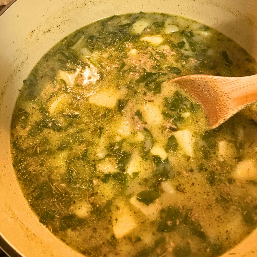 Turkey Potato Spinach Soup in dutch oven with a large wooden spoon