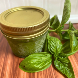 Small frozen jar of pesto with basil next to it
