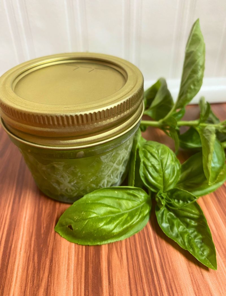 Small frozen jar of pesto with basil next to it