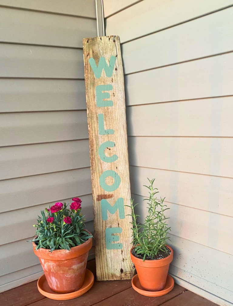 DIY welcome porch sign on porch next to flower pots