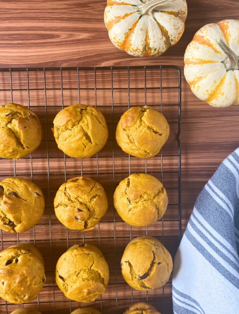 Sourdough pumpkin muffins on cooling rack next to small pumpkins